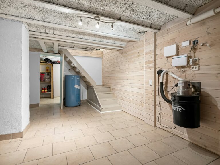 Water heater beside stairs in a finished residential utility room.