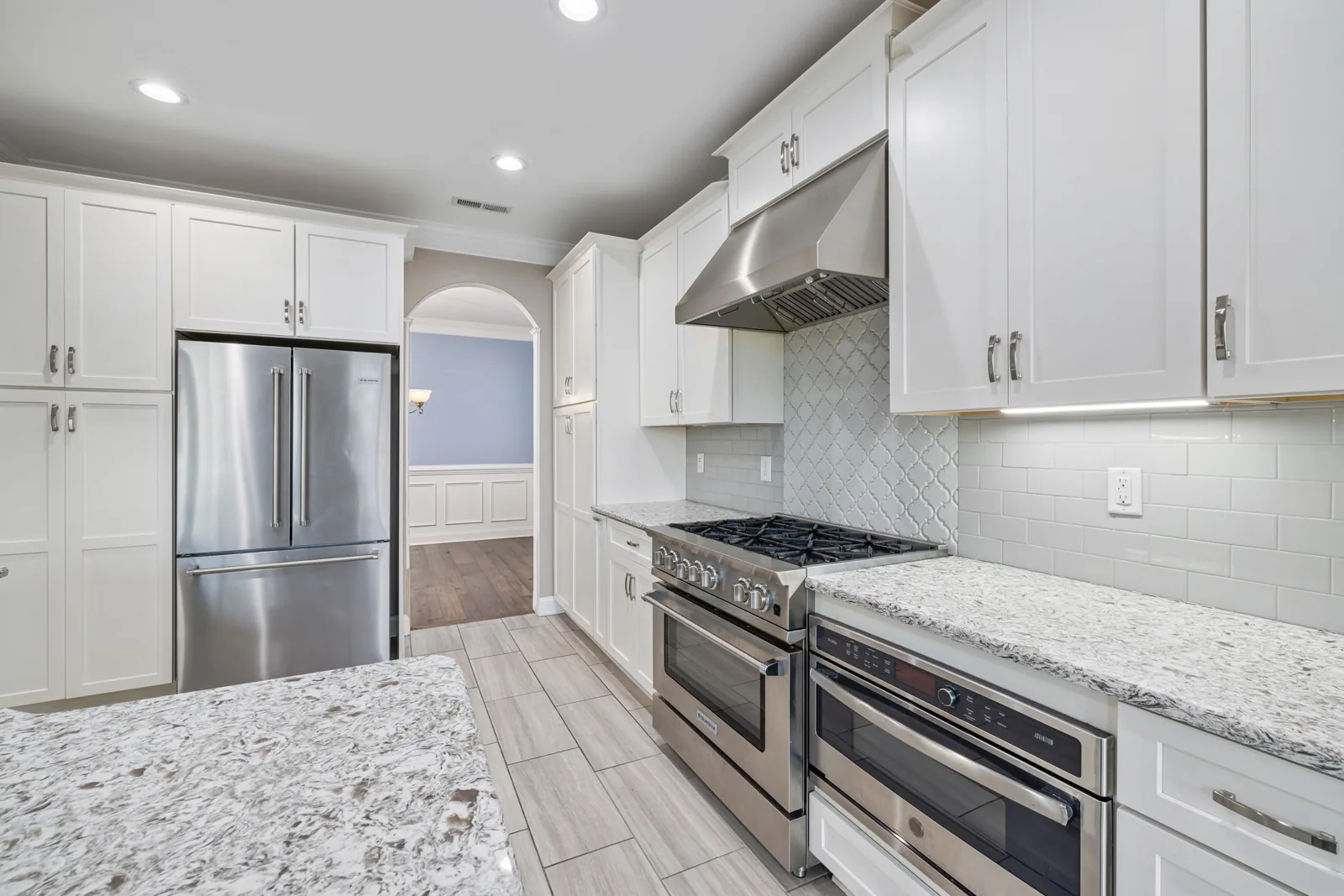 Finished kitchen with white cabinetry, stone countertops and stainless appliances.